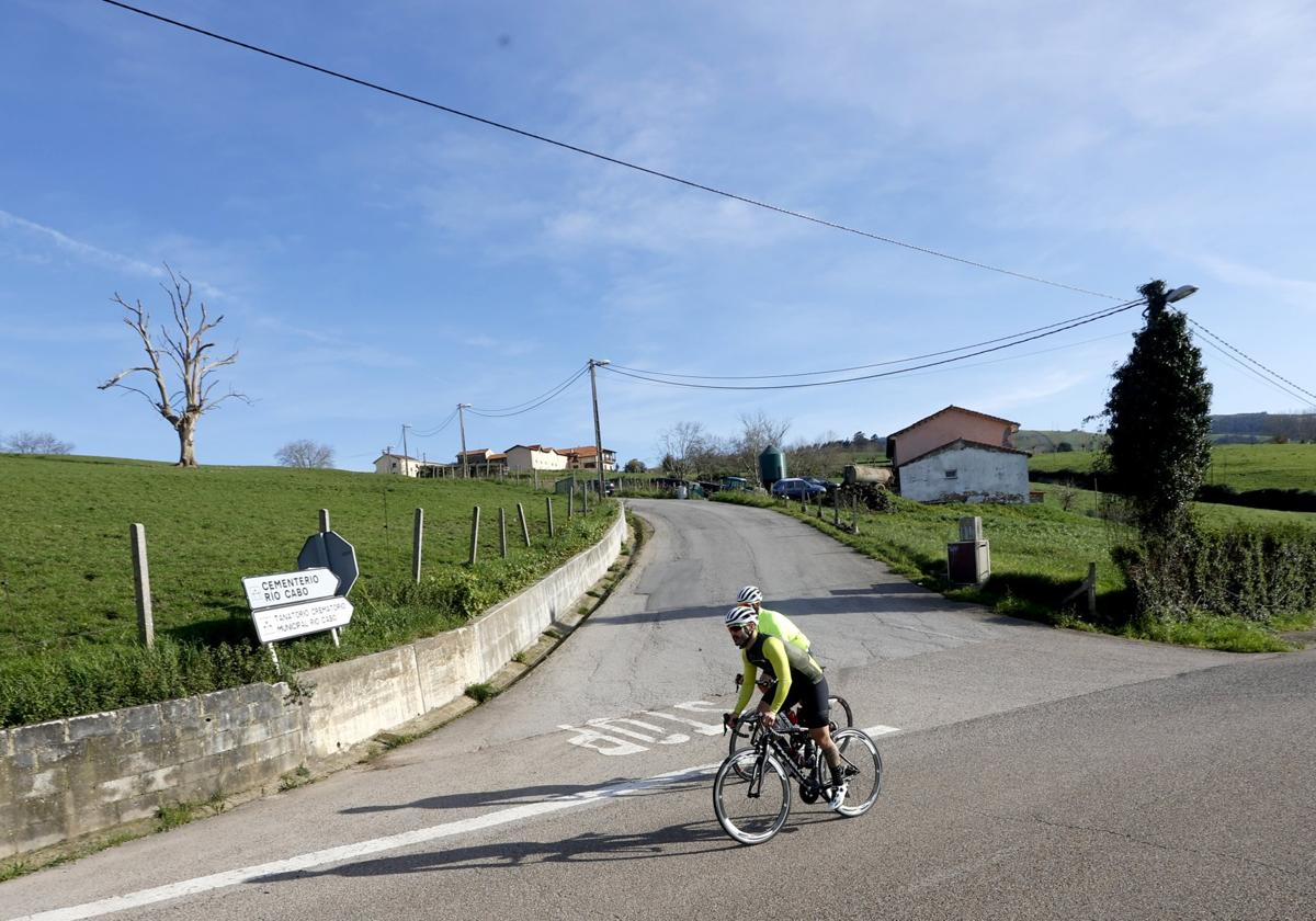 Dos ciclistas pasan junto a la carretera de acceso a Río Cabo.