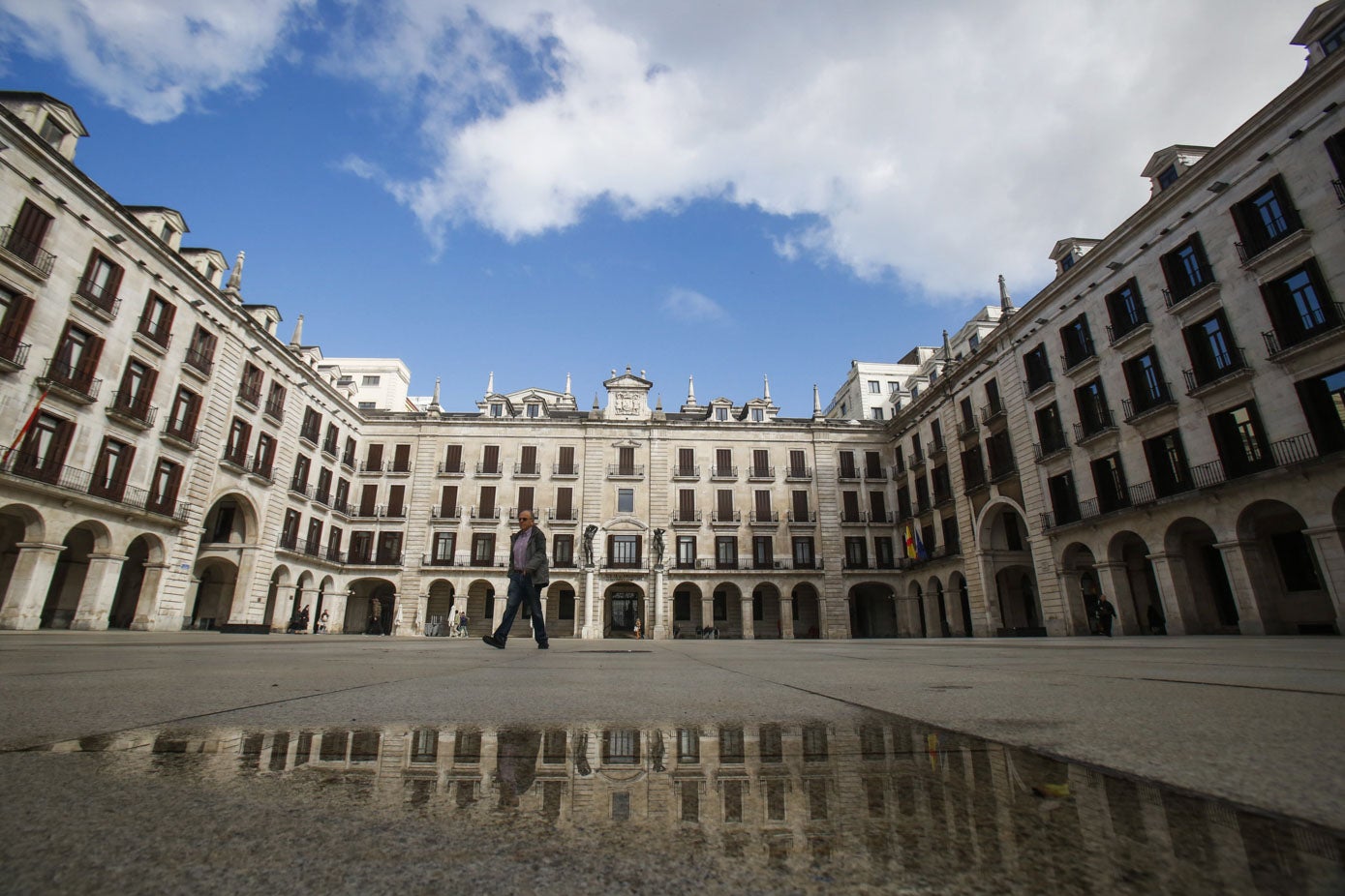 Sólo un viandante pasea por la Plaza Porticada de Santander, lugar habitualmente bullicioso y lleno de actividad.