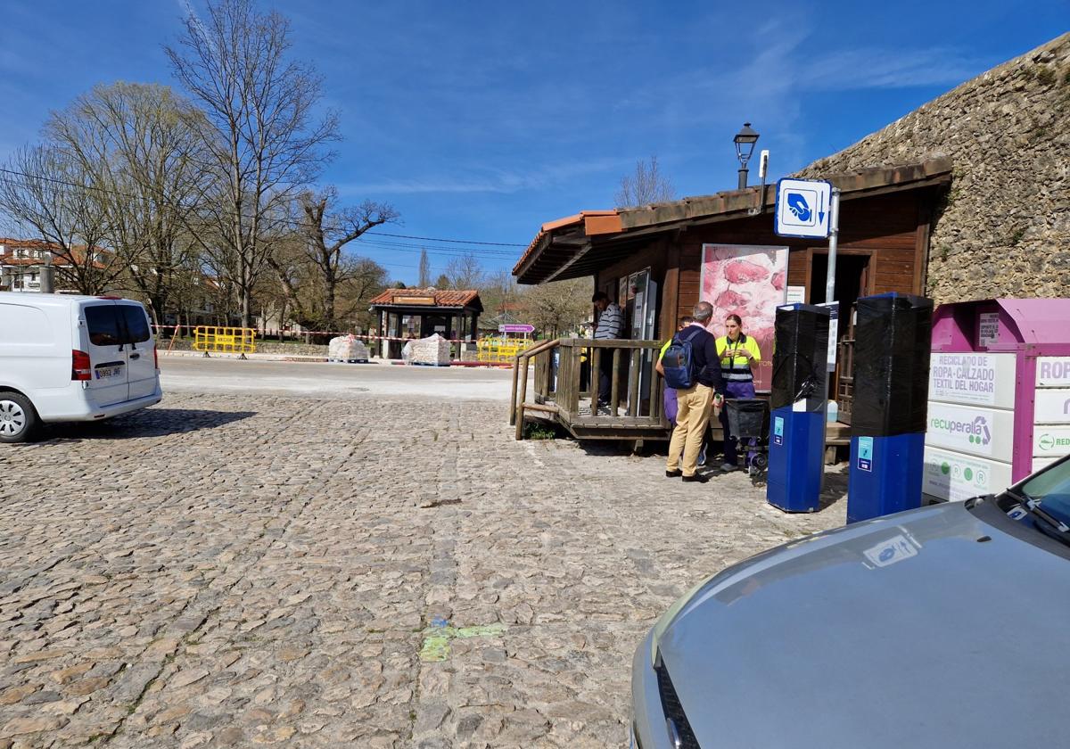 Operarios encargados de gestionar el aparcamiento de Santillana atienden a una persona en la Plaza del Rey.