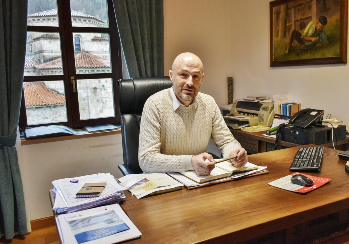 Óscar Villegas, alcalde de Puente Viesgo, en su despacho, con la iglesia de San Miguel al fondo.