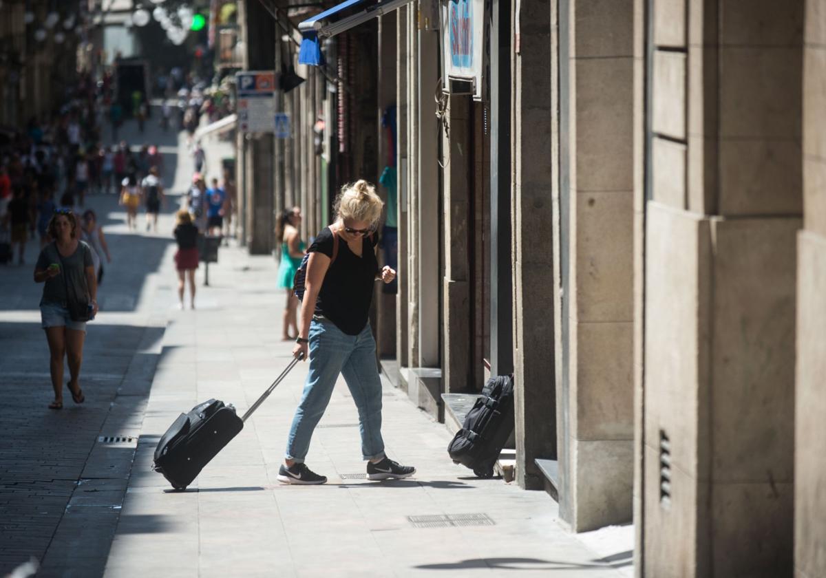 Una mujer entra con su maleta a un piso turístico.