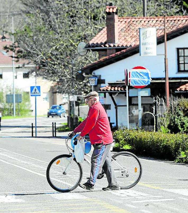 Imagen secundaria 2 - A la izquierda, un camión adelanta a dos ciclistas en el alto de Quijas. Y a la derecha, Un vecino pasa con su bicicleta en un paso de cebra en Casar de Periedo. 