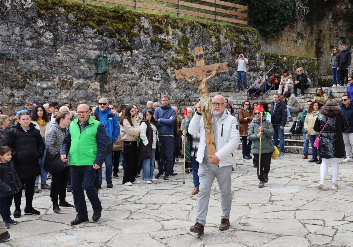 Un devoto traslada la cruz procesional en la explanada del monasterio