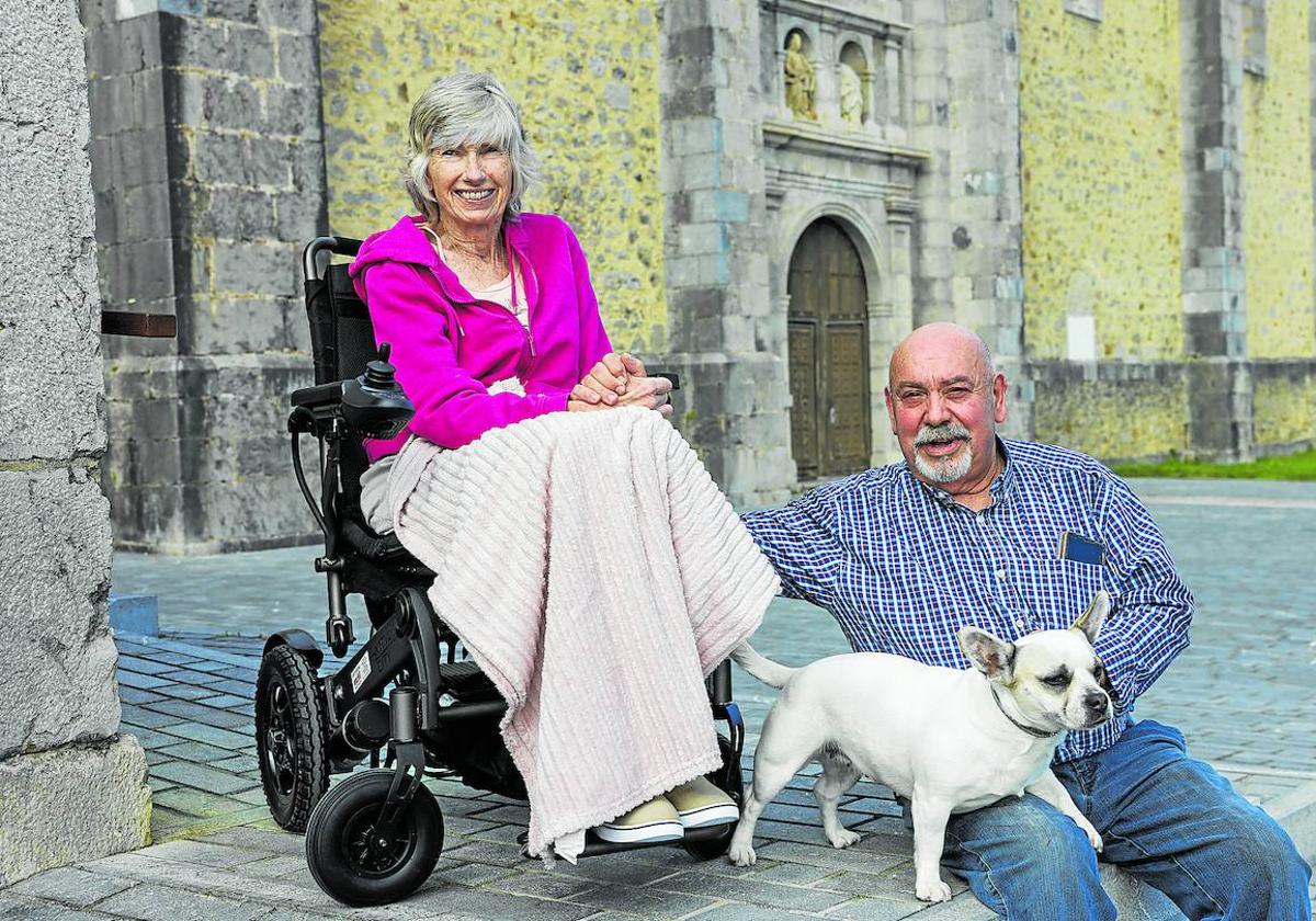 Silvia y Felipe, junto a su perro, en el exterior del albergue de Isla y con la iglesia de San Julián y Santa Basilisa de fondo.