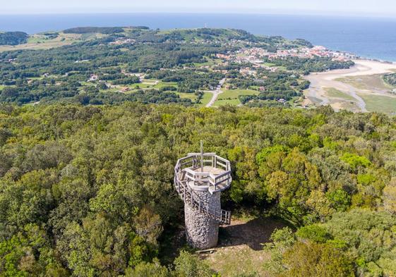 La cima del monte Cincho, en Arnuero, con un manto de encinas y la playa de El Sable de fondo.