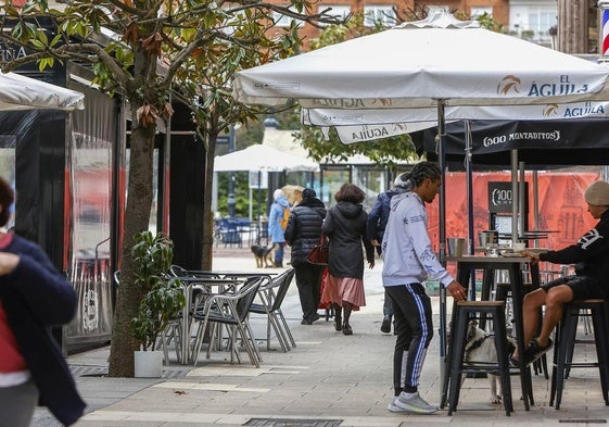 Vecinos caminan junto a una terraza de un establecimiento, en Torrelavega.