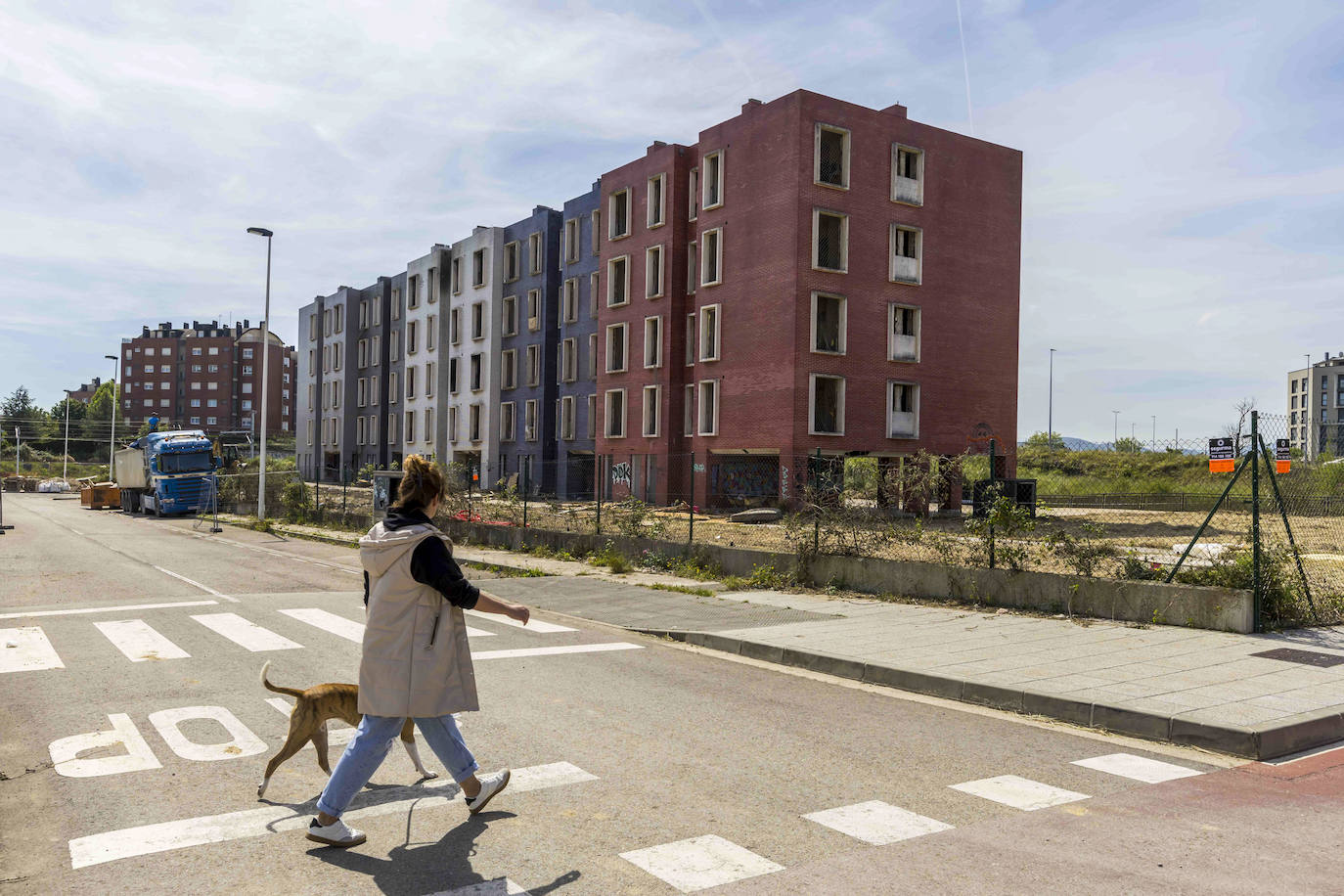 Una mujer pasea con su perro por el entorno del edificio.