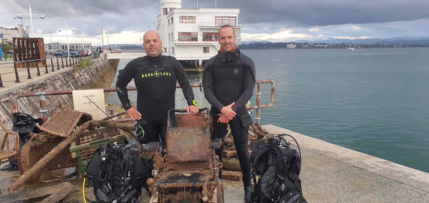 Dos de los buceadores posan con los residuos recuperados del mar.