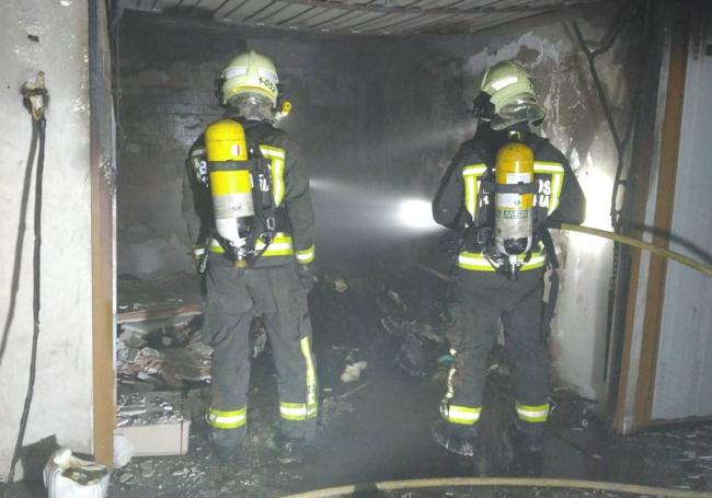 Los bomberos intervienen en el interior del garaje incendiado, totalmente calcinado.