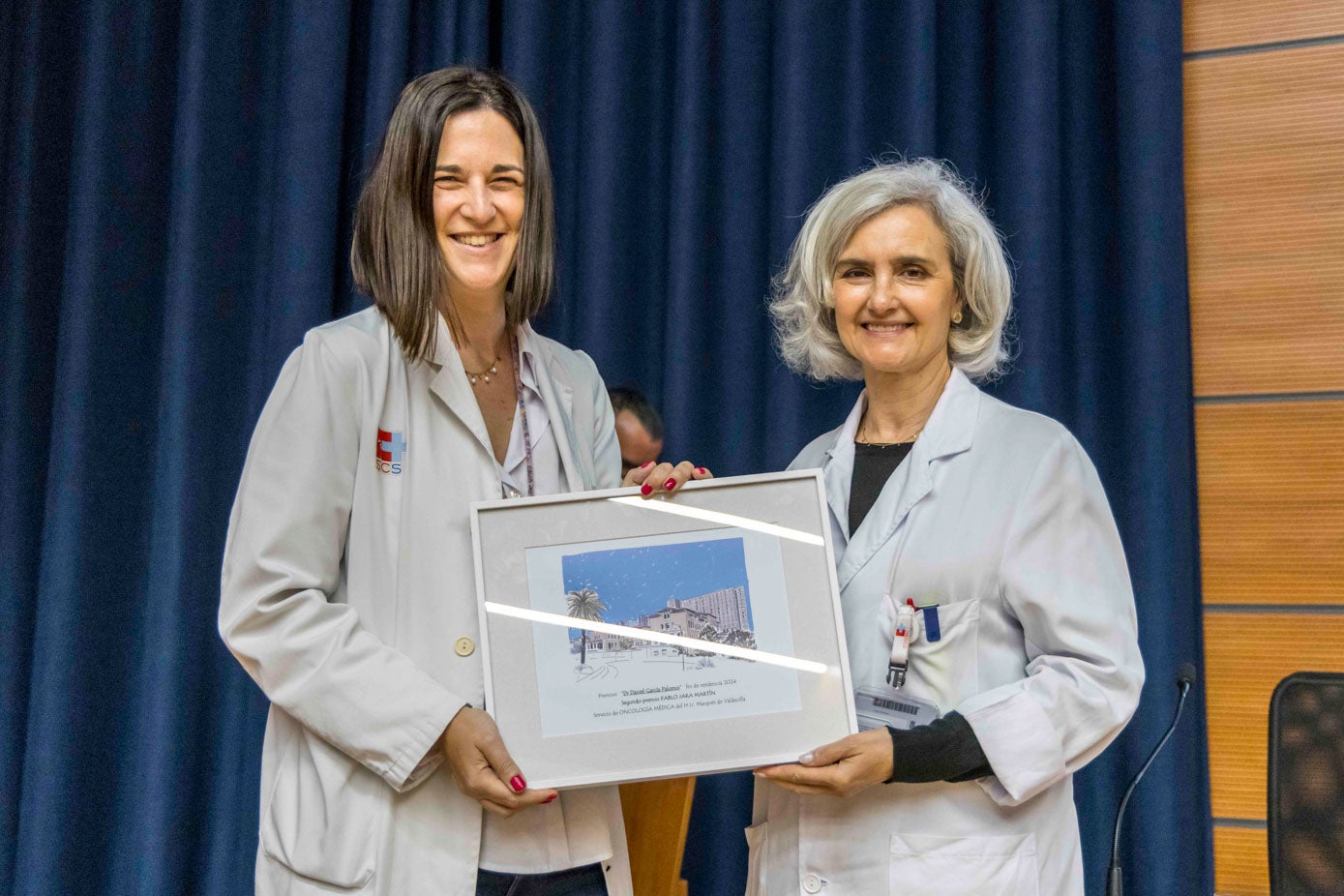 La gerente de Valdecilla junto a la tutora de Oncología posando con el segundo premio otorgado a Pablo Jara, el ya oncólogo que no pudo asistir.