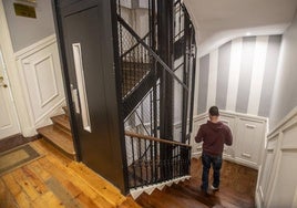 Un vecino baja por la escalera con la puerta del ascensor del edificio en primer plano.