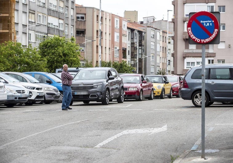 Un hombre espera, delante de su coche, a que se libere una plaza.