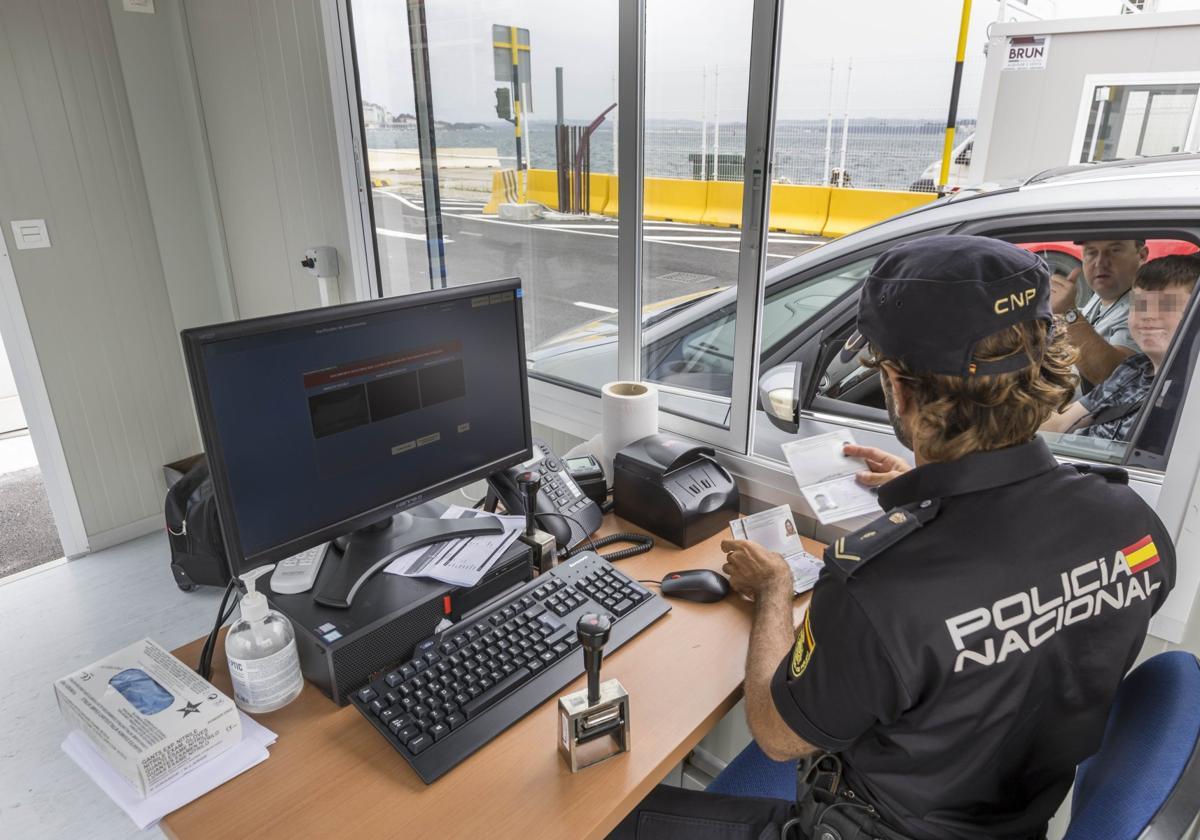 Un policía nacional chequea un pasaporte en el actual control de fronteras del Puerto de Santander.