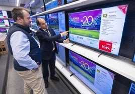 Un vendedor enseña untelevisor a un cliente, en El Corte Inglés.