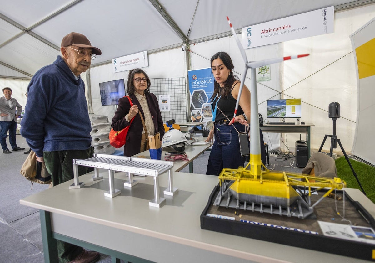 Dos de los primeros visitantes atienden las explicaciones en el expositor de Ferrovial.