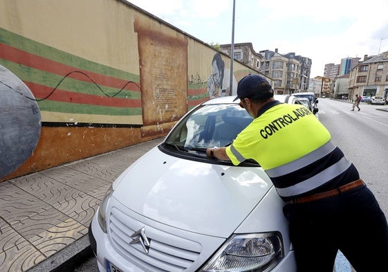 Uno de los controladores del servicio coloca un aviso en un vehículo indebidamente aparcado, este miércoles, en una de las zonas de carga y descarga afectada por el Estacionamiento Regulado Activo (ERA).