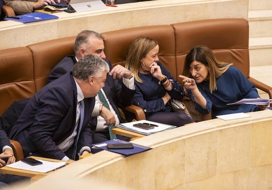 Buruaga charla con los consejeros de Economía, Fomento y Presidencia durante un pleno del Parlamento regional.