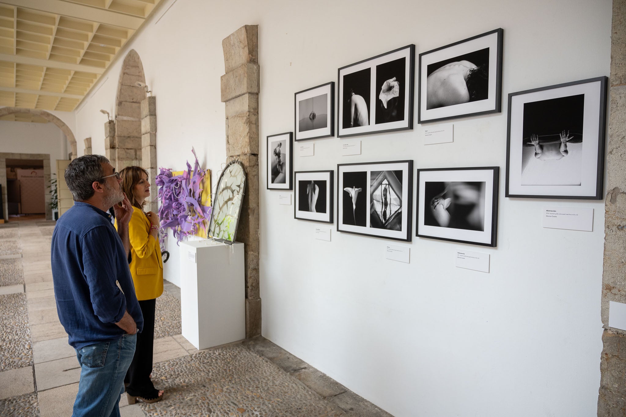 Dos visitantes observan las fotografías de Marina Cuesta