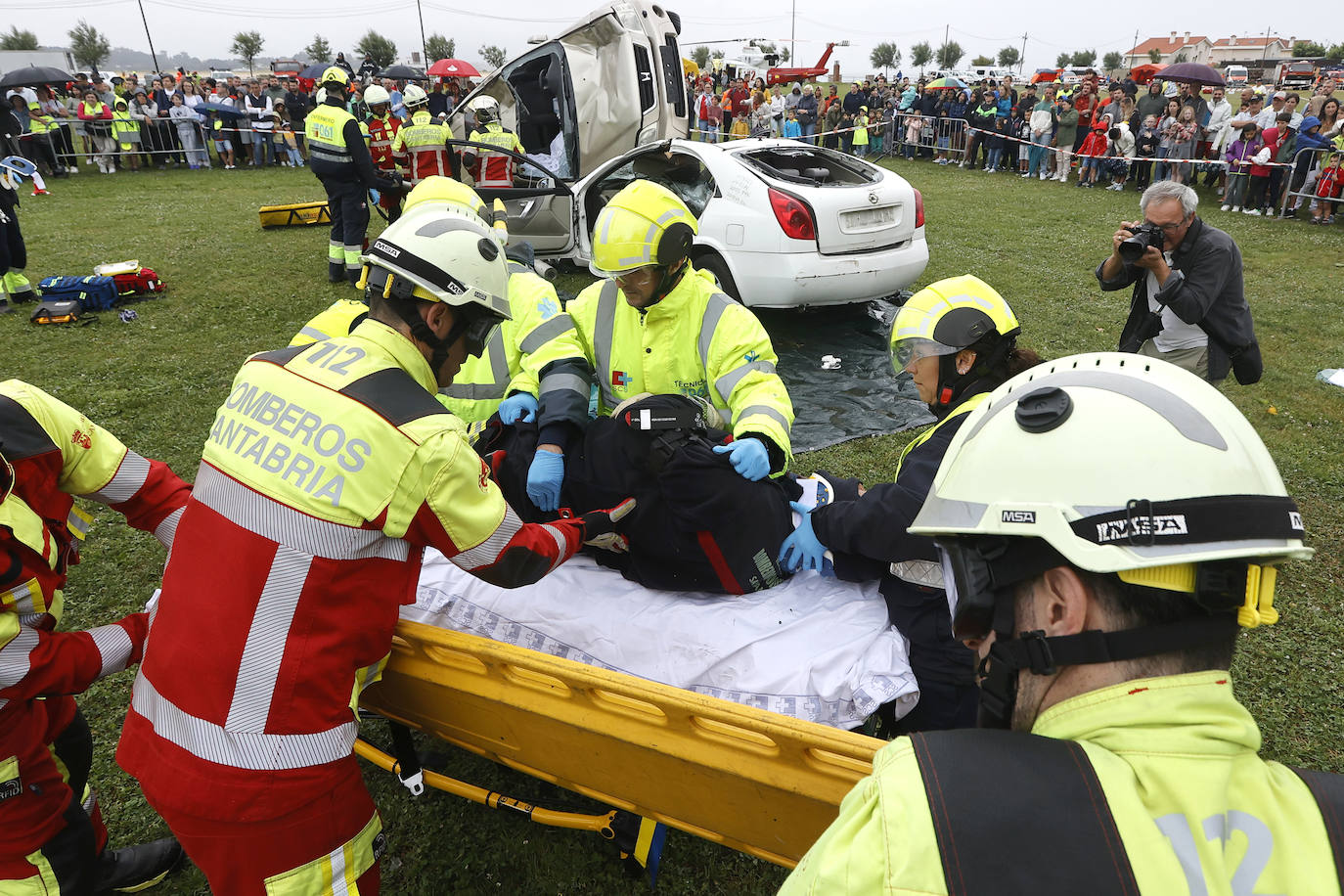 Bomberos y personal sanitario trasladan a un herido a la camilla para su atención y traslado.