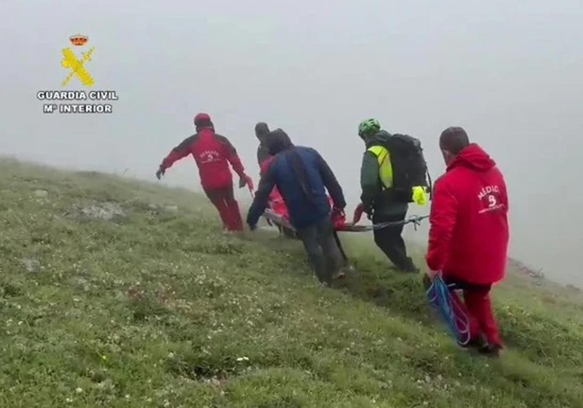 Efectivos de bomberos y agentes de la Guardia Civil portean el cadáver del hombre.