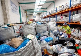 Un operario se encarga de apilar lotes de ropa, en las instalaciones municipales del servicio en Barreda.