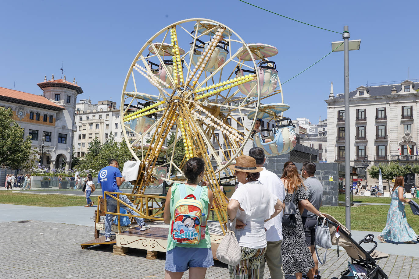 Un grupo de niños disfruta de la noria de la Plaza de Alfonso XIII ante la atenta mirada de sus familiares