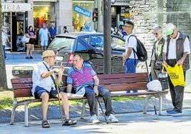 Un grupo de personas mayores descansa en los bancos de la plaza del Ayuntamiento de Santander.