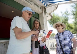 Cristina atiende a dos turistas en la oficina de El Sardinero situada junto a la Primera playa.