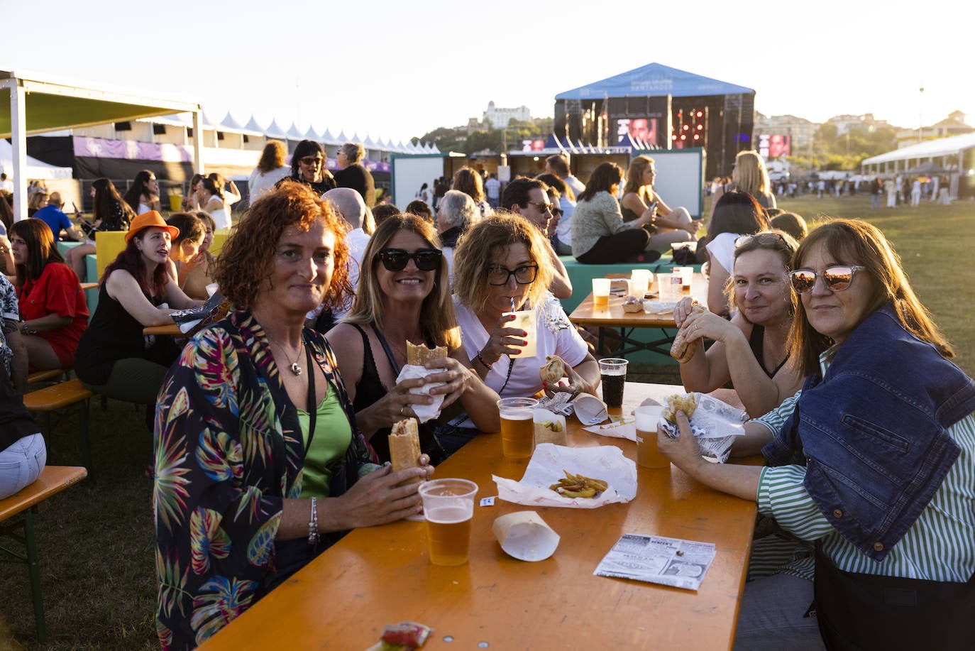 Un grupo de amigas posa con sus bocadillos y bebidas antes de la actuación. 