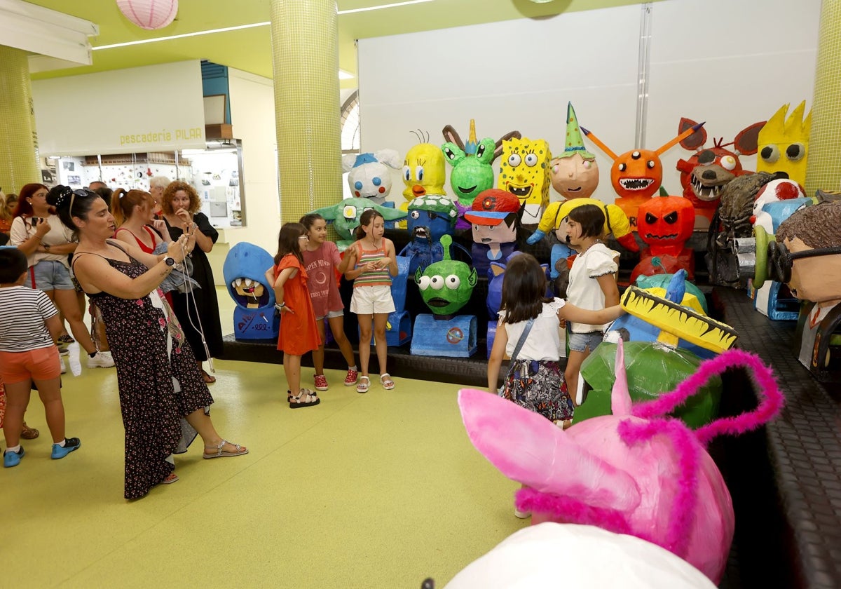 Los jóvenes artistas y sus familias se hacen fotos con las creaciones, este miércoles, en el mercado municipal.