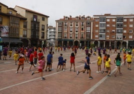 Niños y monitores juegan durante una de las actividades celebrada en la plaza Baldomero Iglesias de Torrelavega, en el día inaugural del Campamento Urbano del SOAM.