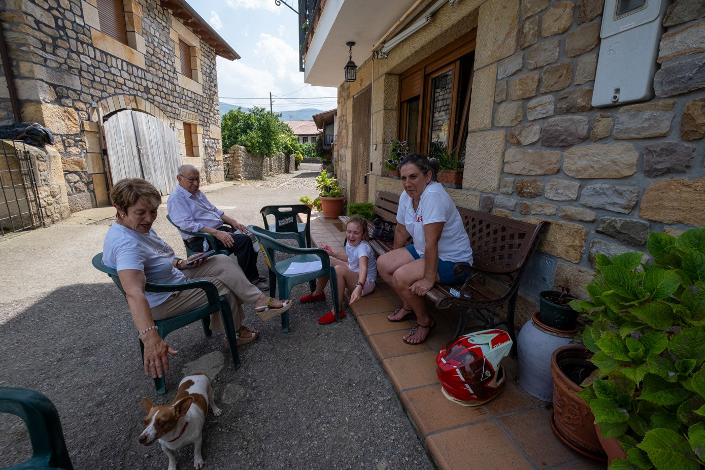 Una familia se refugia del sol en la entrada de su vivienda.