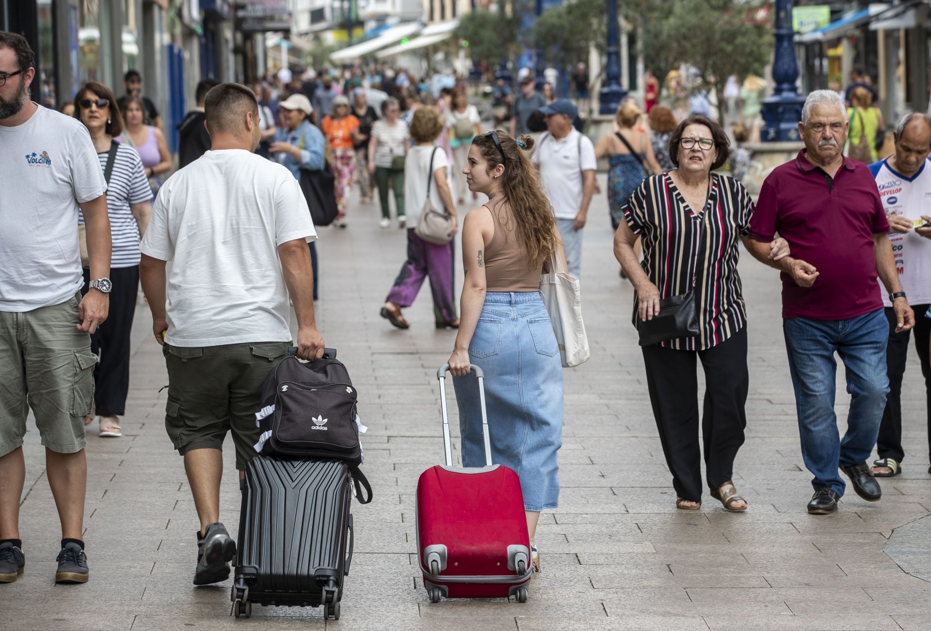 Una pareja por la calle con sus maletas.