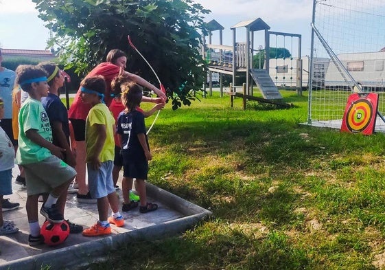 Un grupo de niños del camping jugando a tiro con arco en el área de multideporte.