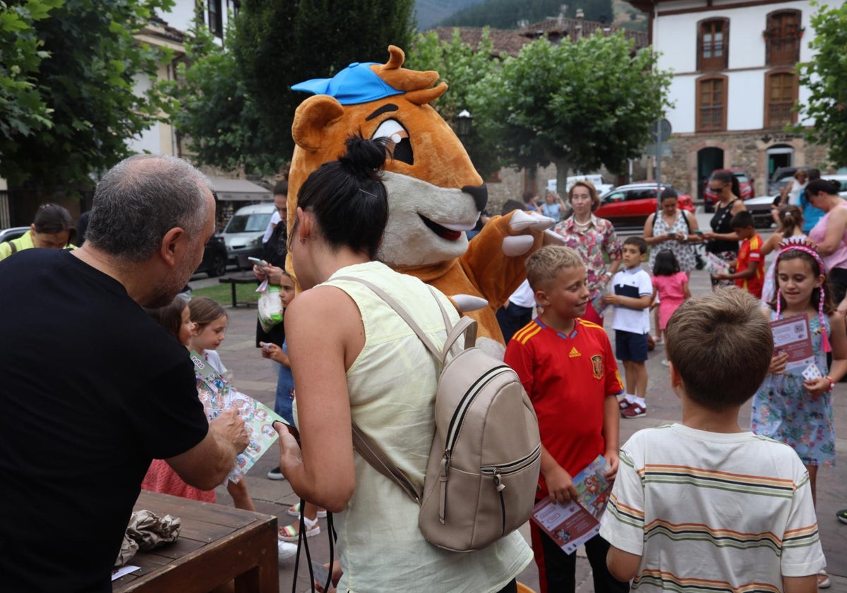 Imagen principal - Dos momentos de la presentación del juego y el alcalde de Potes junto al niño ganador del concurso de la portada y la mascota del juego 