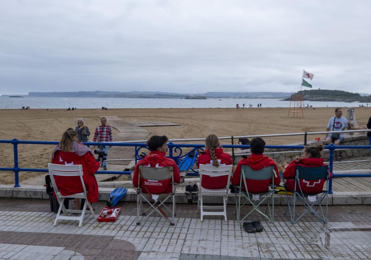 Los socorristas, con cazadoras, observan, la playa de El Sardinero, vacía por el mal tiempo