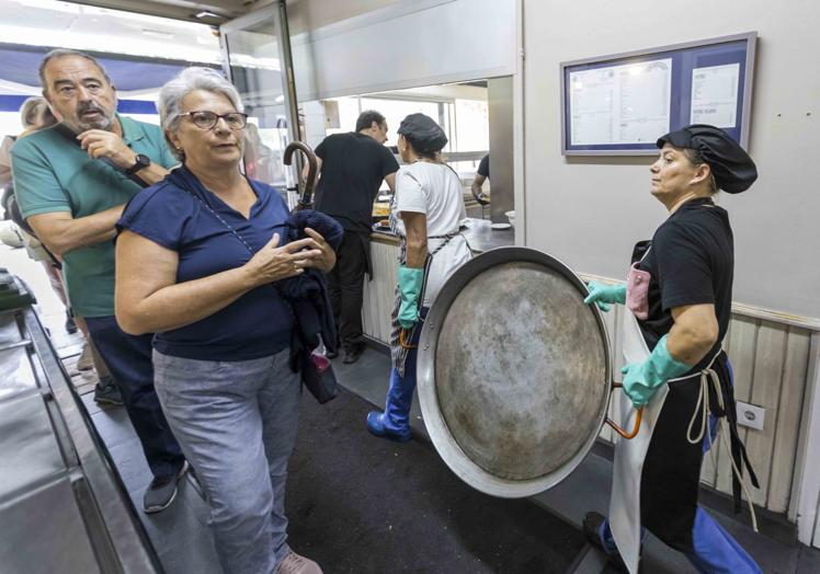 Largas esperas. Las paelleras pasan por al lado de los clientes que esperan a que se libere una mesa para comer.