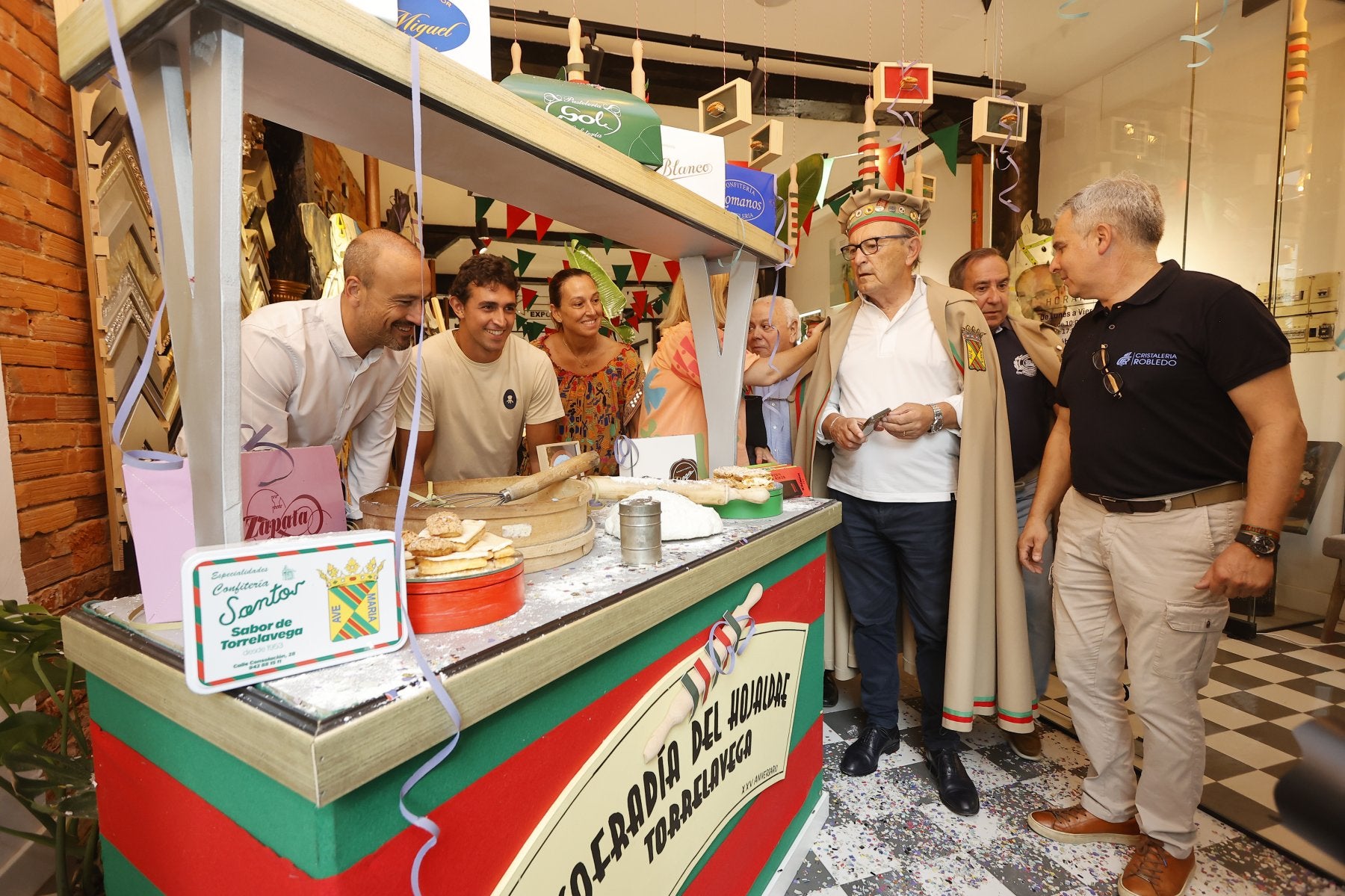 Autoridades y cofrades disfrutan de la muestra en Cristalería Robledo durante su inauguración.