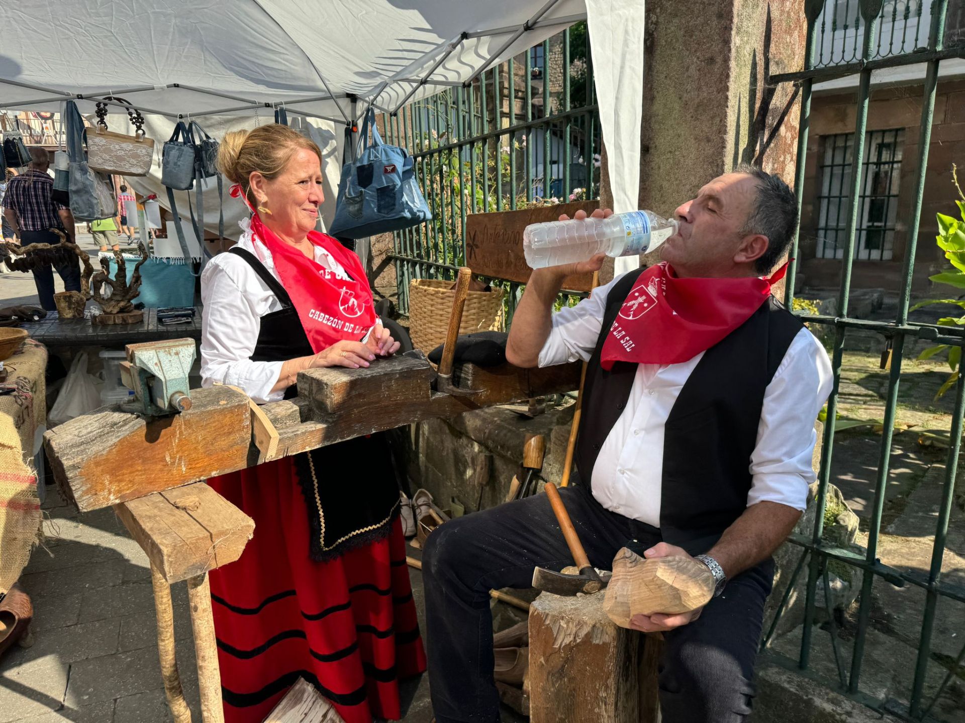 Dos participantes en el Día de Cantabria, celebrado en Cabezón de la Sal, se hidratan para combatir el sofoco. 