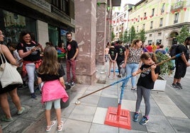 Una niña trata de coger objetos en el suelo con un gancho, uno de los juegos artesanales en la Plaza Mayor.