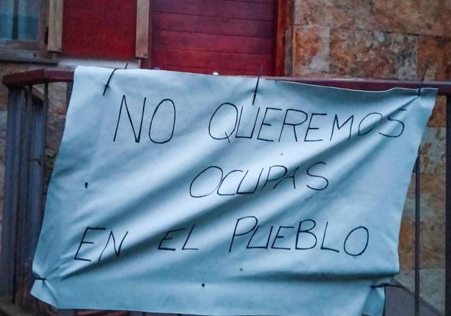 Pancarta que los vecinos han puesto en la vivienda okupada.