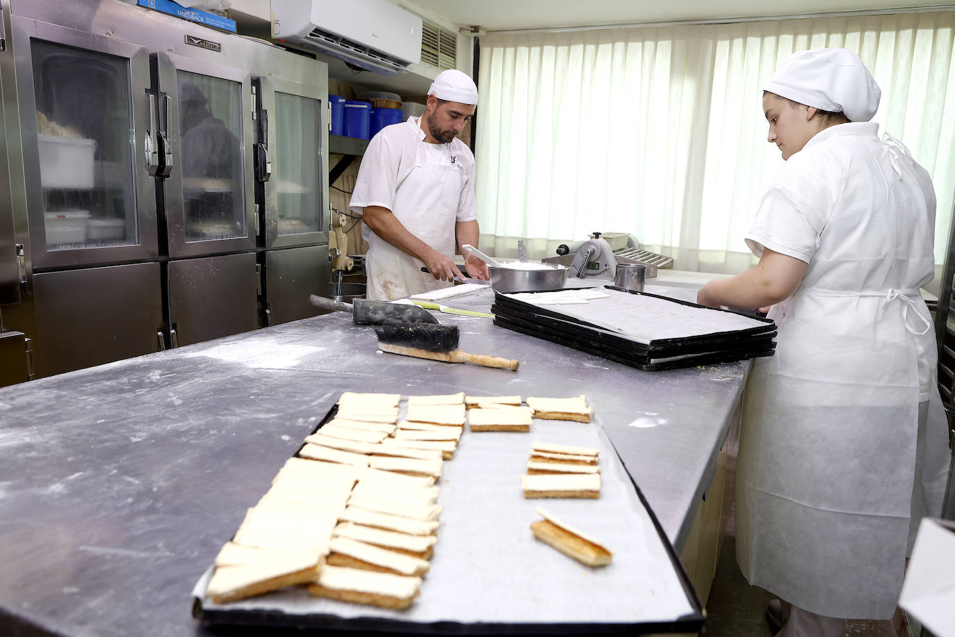 Confiteros de Santos trabajan en distintos dulces, con una bandeja de polkas en primer término.