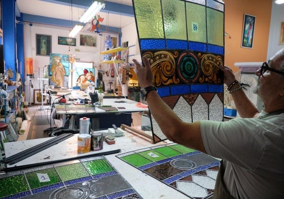 El vitralista muestra una de las vidrieras en restauración en una de las mesas de su taller, ubicado en Torrelavega.