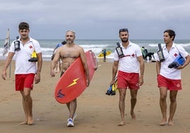 Los tres socorristas de Canallave (Daniel, Daniel y Juan) junto al surfista David Vega, que porta la tabla con la que ha sacado del agua a cuatro personas en los últimos tres días.