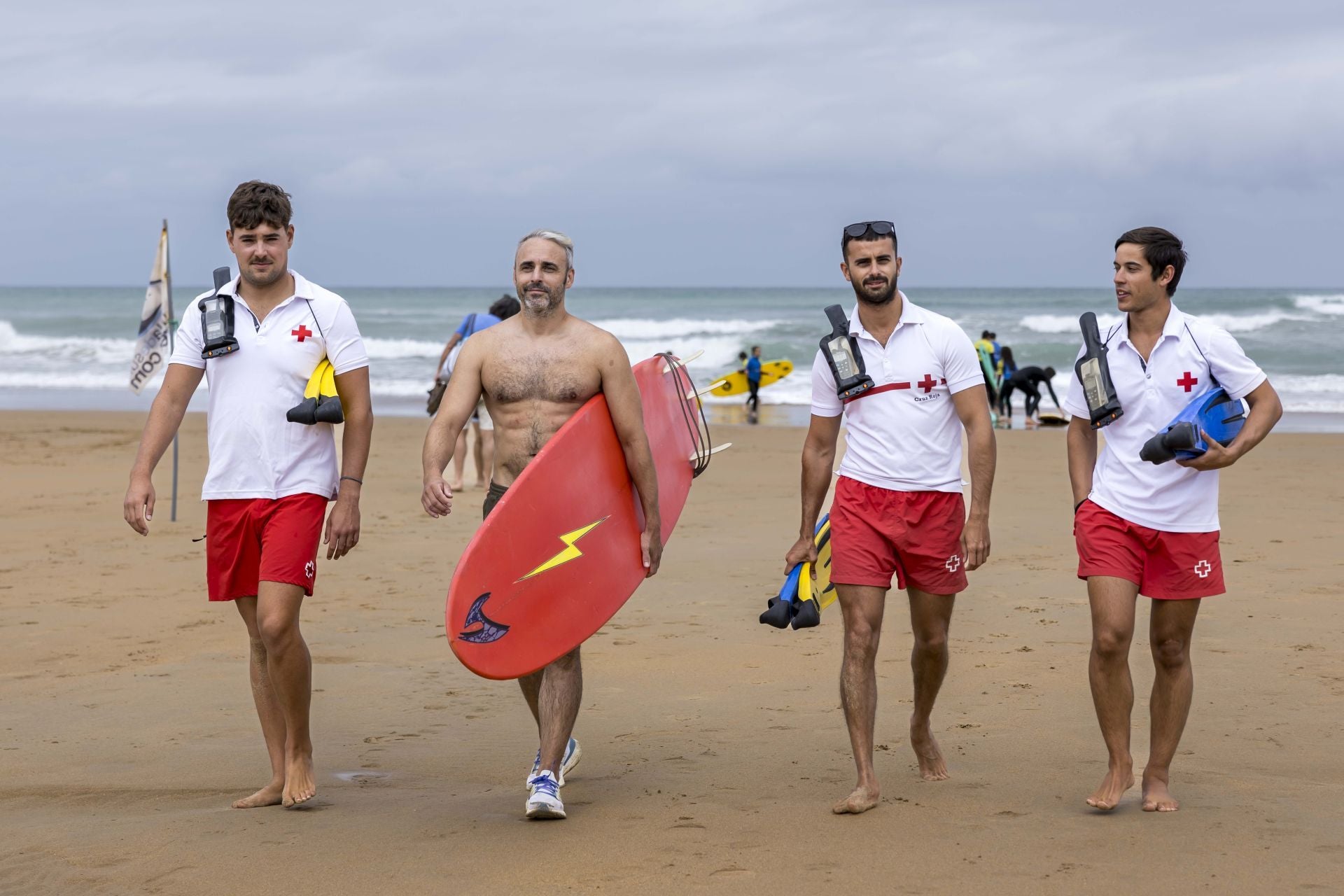 Los tres socorristas de Canallave (Daniel, Daniel y Juan) junto al surfista David Vega, que porta la tabla con la que ha sacado del agua a cuatro personas en los últimos tres días.