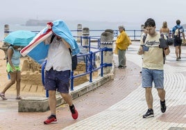 La gente sale espantada por la lluvia de la playa de El Sardinero el pasado sábado.