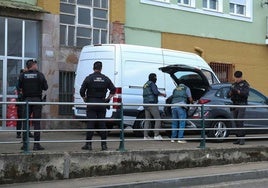 Agentes encapuchados introducen material intervenido en el maletero de un coche.