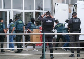 Agentes, algunos encapuchados, depositan en una furgoneta cajas con material incautado en la casa de uno de los detenidos, en Torrelavega.