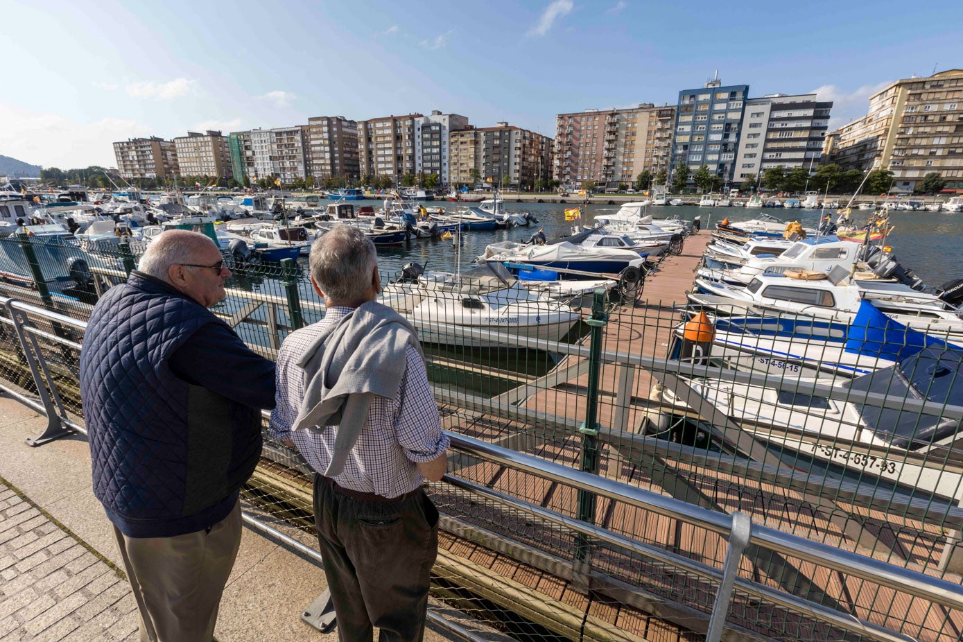 Dos viandantes se fijan en la subida del agua en el los muelles del Barrio Pesquero.