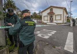 Dos agentes de la Guardia Civil acordonan una vivienda en Hinojedo donde apareció muerta una mujer.